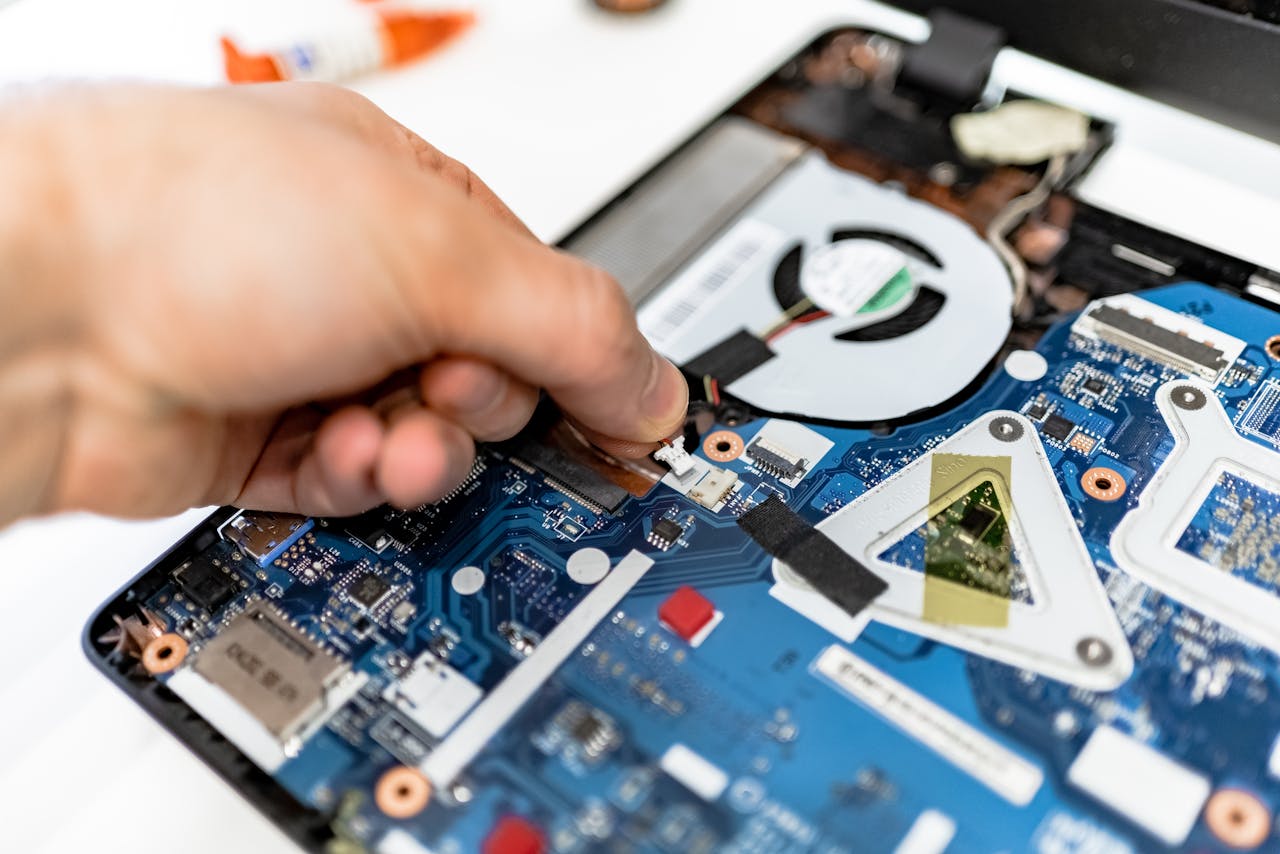 about-img Close-up view of a hand fixing a computer motherboard showcasing technology and electronics repair.
